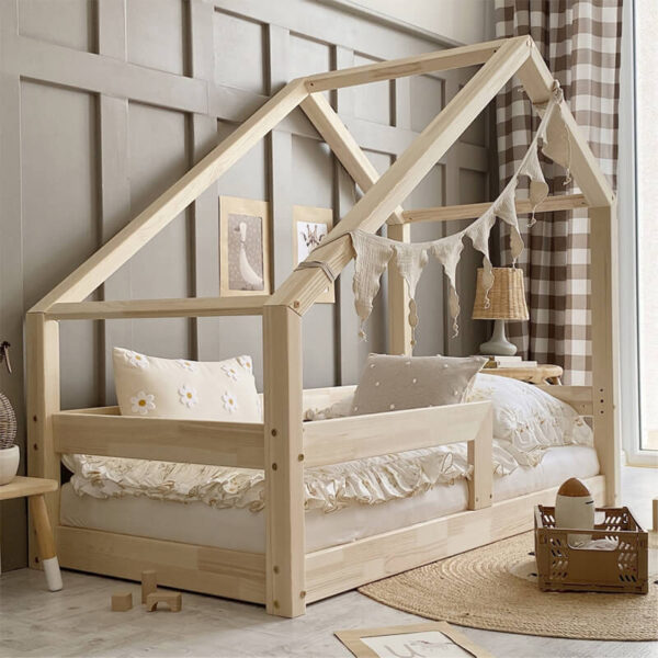 Ein Hausbett aus hellem Holz mit einer Schutzleiste für mehr Sicherheit in einem beigen Zimmer